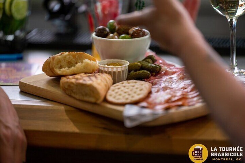 A charcuterie board with various meats, olives, and crackers on a wooden board. 3