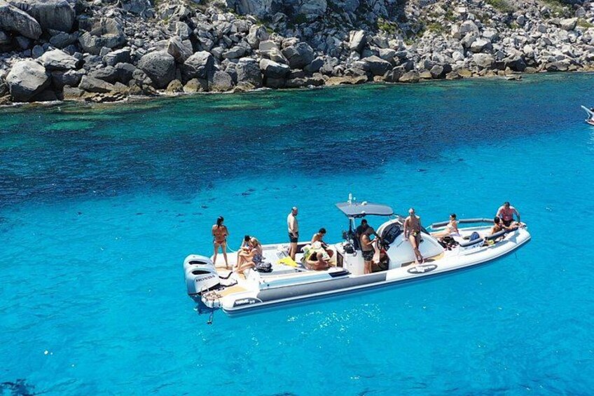 Un bote con gente en un mar turquesa, rodeado de rocas. 2