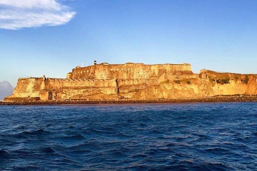 A coastal fortification with a large wall and a watchtower, overlooking the sea. 4