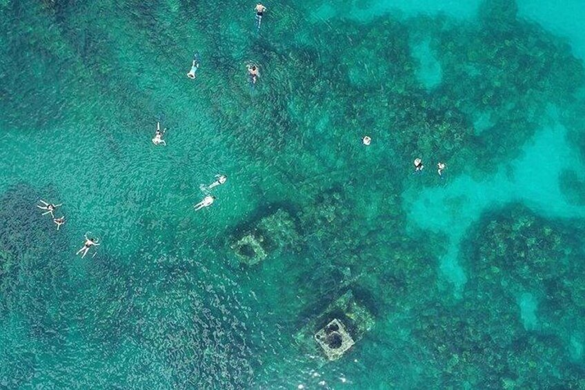 Un mar turquesa transparente con varias personas nadando y haciendo snorkel. 2
