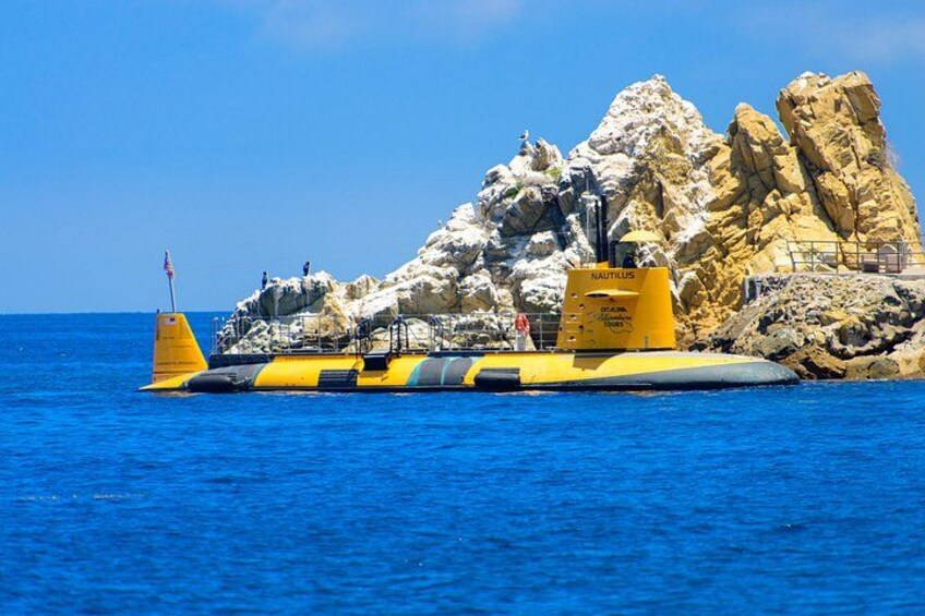 A yellow and black vessel with a yellow buoy labeled 'NAUTILUS' near rocky cliffs. 2