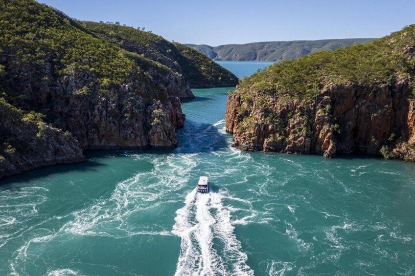 A boat navigating a narrow waterway flanked by steep cliffs. 5