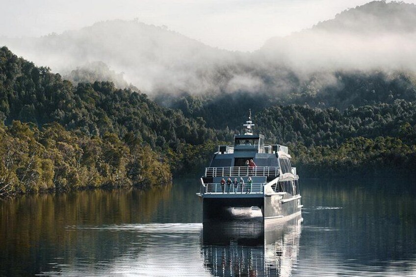 Un bateau sur une étendue d’eau calme, avec une montagne boisée en arrière-plan. 5