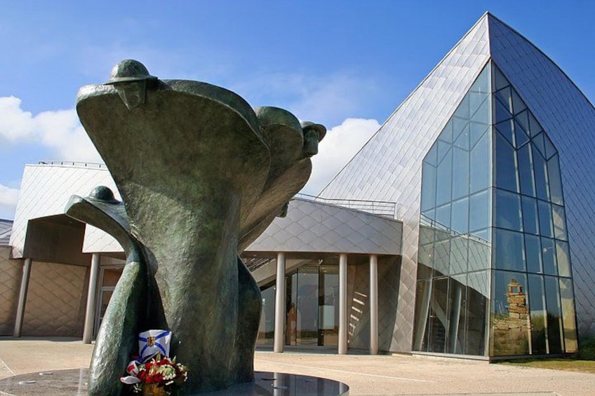 A modern building with a glass facade and a large bronze sculpture in front. 5