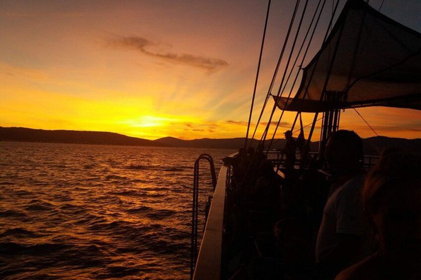 A sunset over water with a boat and people on deck. 4