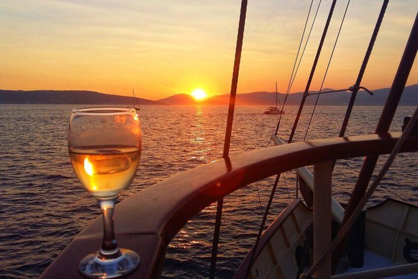 A sunset over water with a glass of white wine on a boat. 3