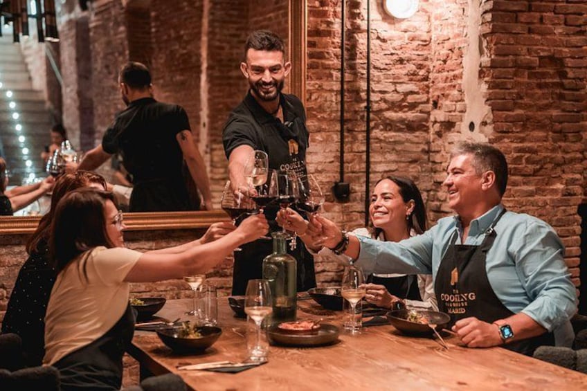 Un gruppo di persone brinda con bicchieri di vino in un ristorante con una parete di mattoni sullo sfondo. 2