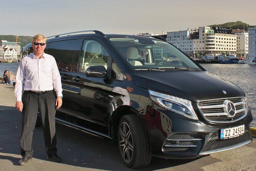 Ein schwarzer Mercedes-Benz SUV steht am Wasserufer, daneben steht ein Mann. 2
