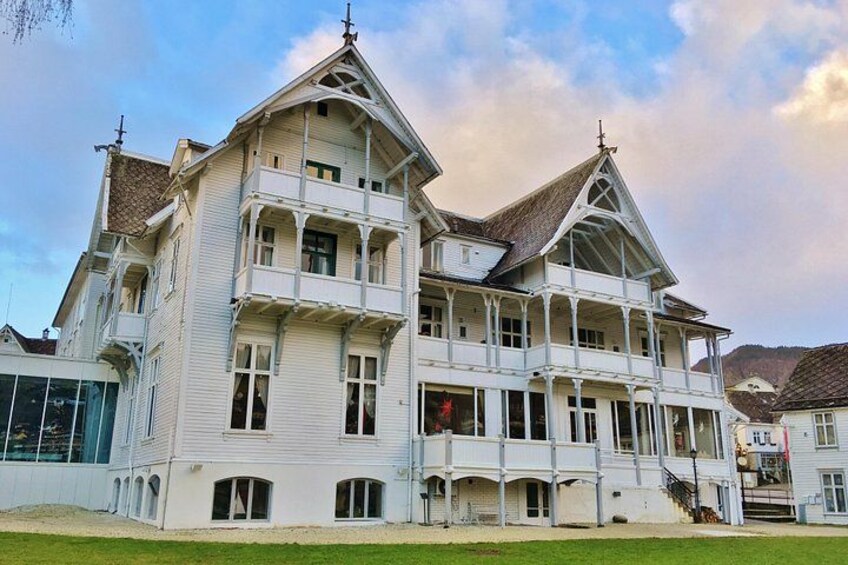 A large, white, multi-story building with a steep roof and multiple balconies. 2
