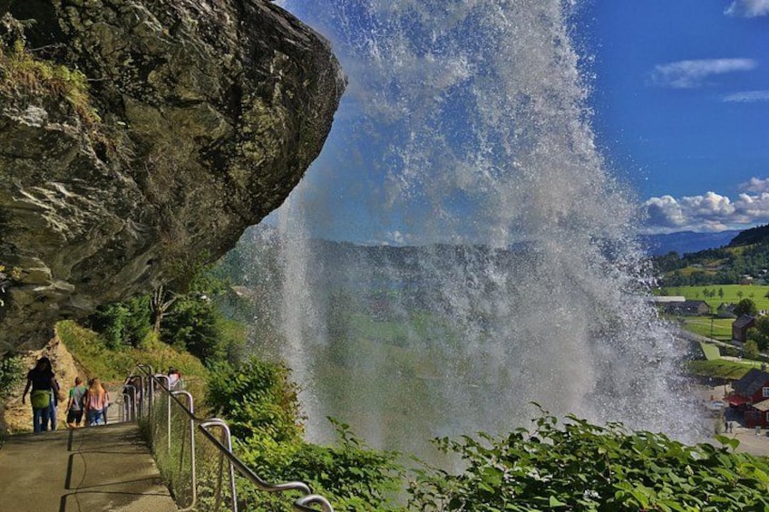 A waterfall cascading over a rocky cliff, with a pathway and railing for visitors. 4