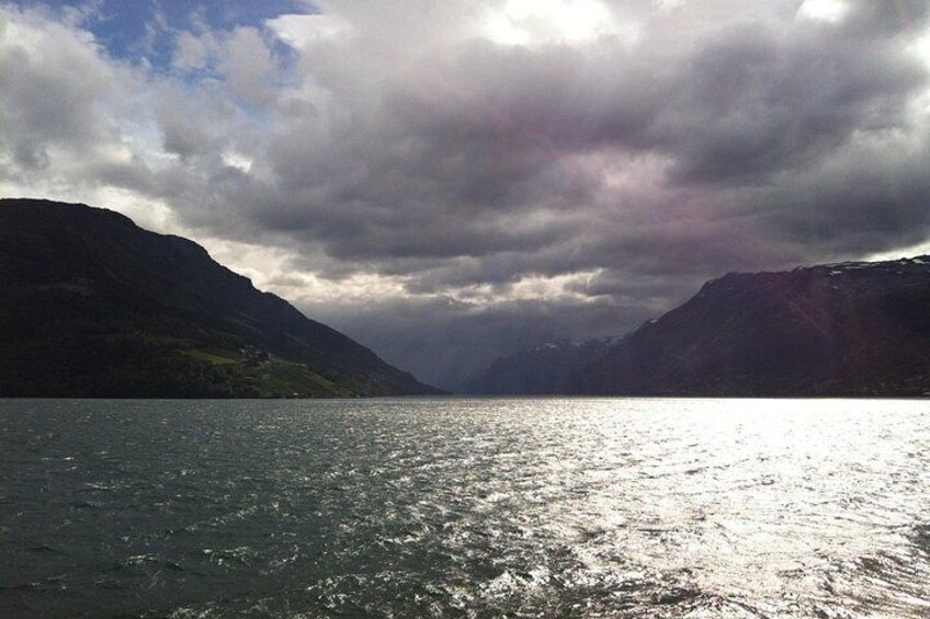 A lake with mountains in the background under a cloudy sky. 4