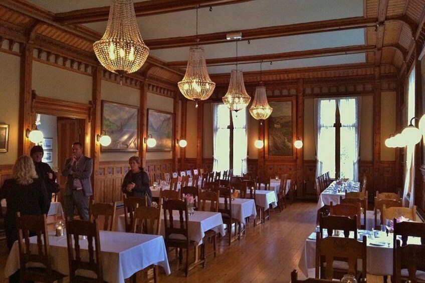 A restaurant with wooden interiors, chandeliers, and tables set for dining. 3