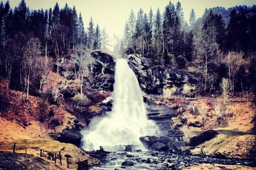A waterfall cascading down a rocky cliff surrounded by trees. 2