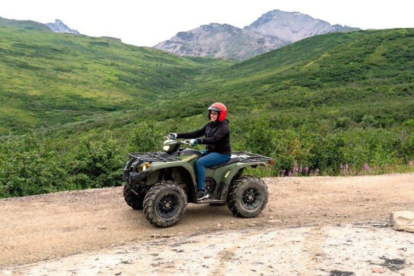 Una persona conduce un cuatrimoto por un sendero de tierra con colinas verdes al fondo. 5