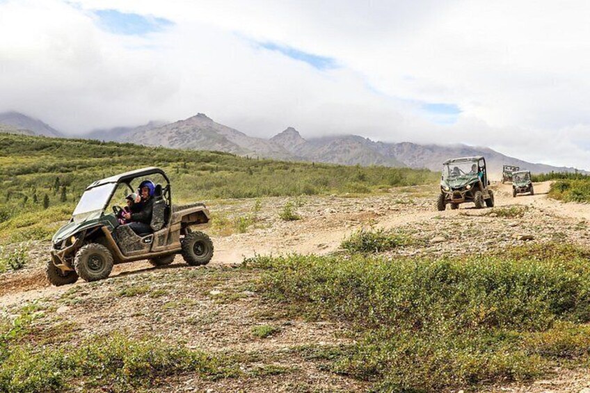 Off-road vehicles on a dirt path with mountains in the background. 5