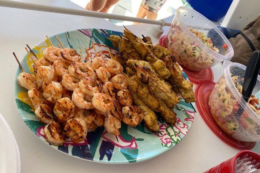 En tallerken med grillede rejer og kyllingespyd, samt to små beholdere med dyppsaucer. 3