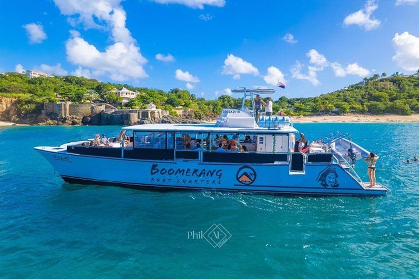 A boat named 'Boomerang' on clear turquoise waters with a coastal landscape in the background. 3