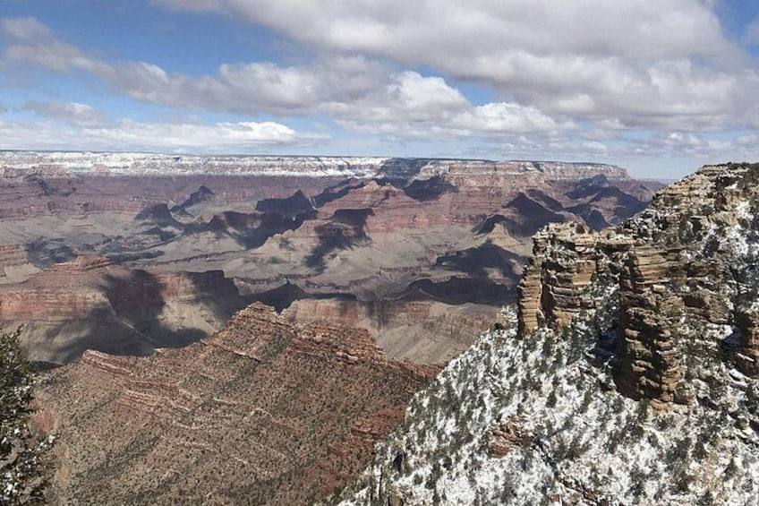A vast canyon with layered rock formations and snow patches. 2