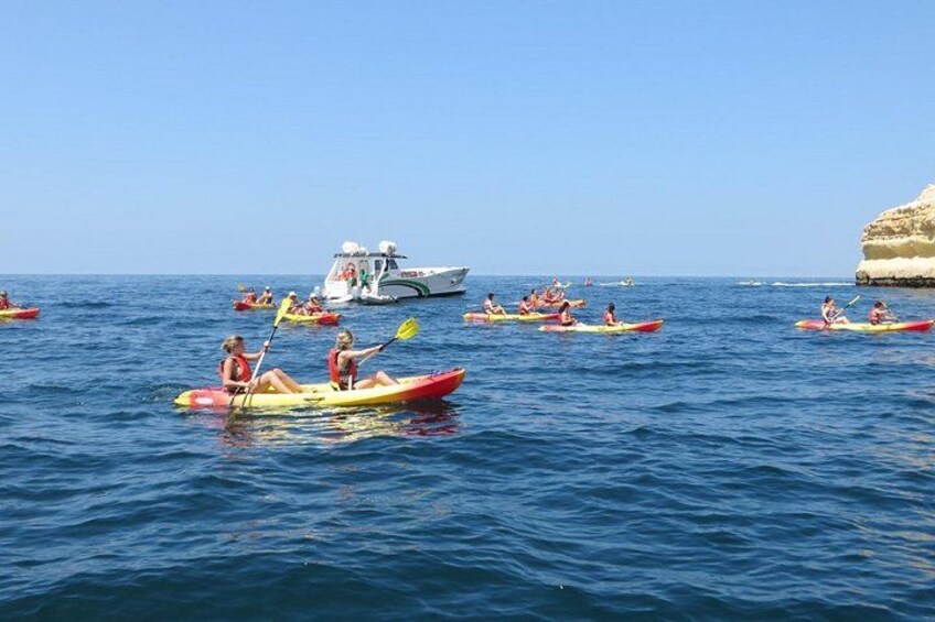 Personas haciendo kayak en un mar tranquilo, con un bote al fondo. 5