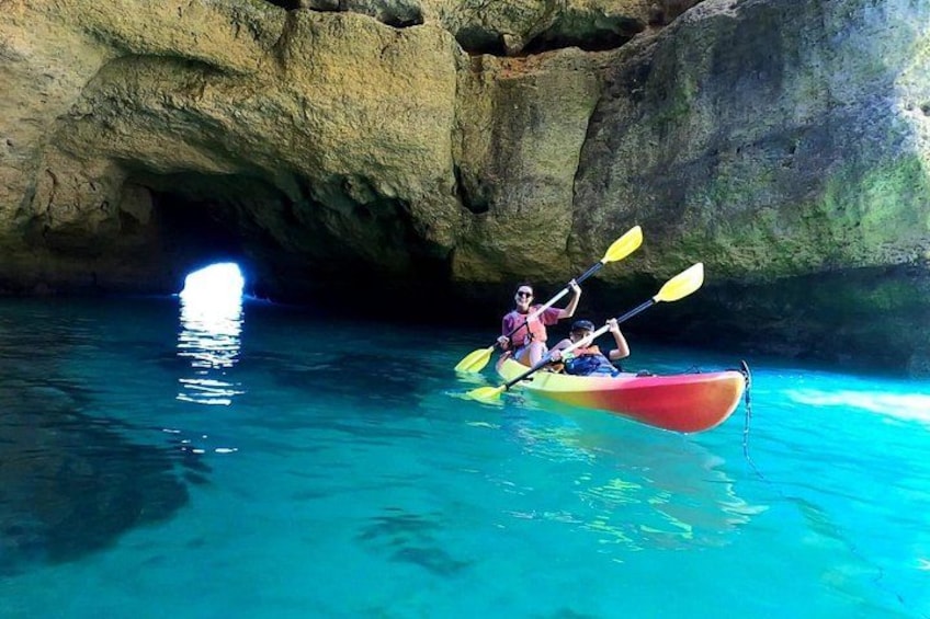 Un kayak en agua azul cristalina con una cueva al fondo. 1