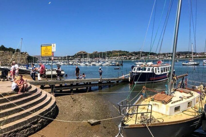 A harbor with boats docked, people walking, and a signboard. 4