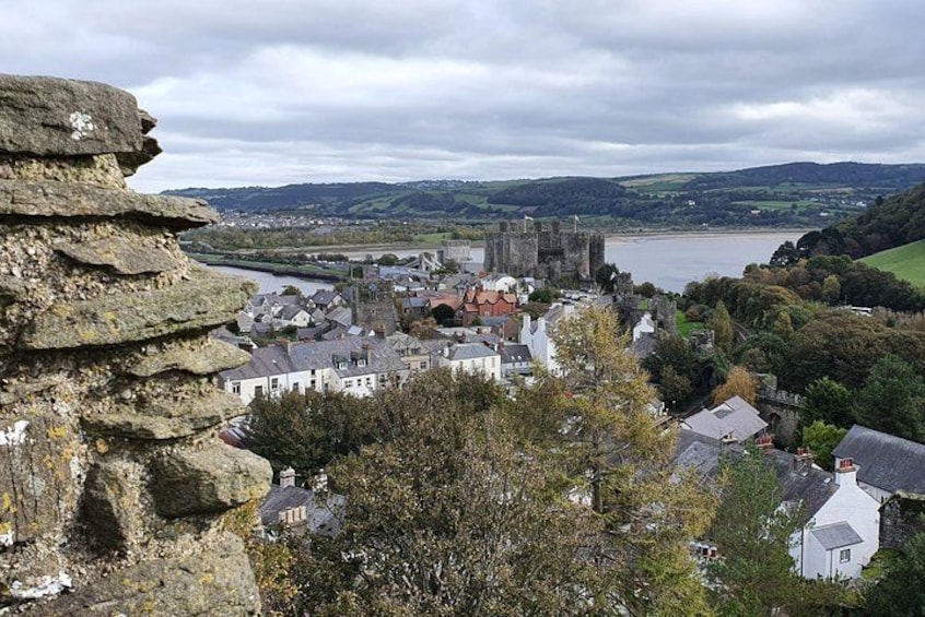 A town with a castle, river, and surrounding hills. 3