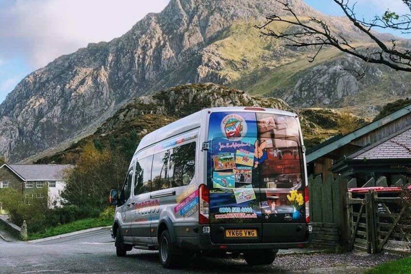 A bus parked on a road with a mountainous backdrop. 4