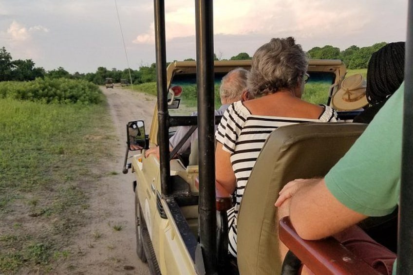 A safari vehicle on a dirt road with passengers. 3