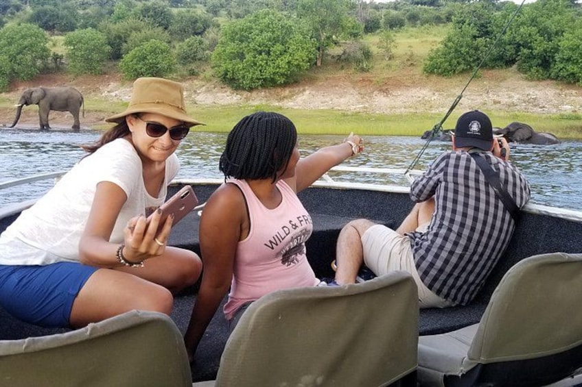 Three people on a boat, one pointing at something, another holding a phone, and a third fishing. 5