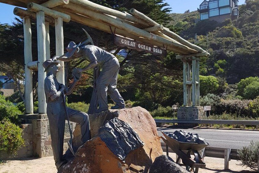 A statue of two men, one sitting and one standing, with a wheelbarrow and a sign that reads 'Great Ocean Road'. 4