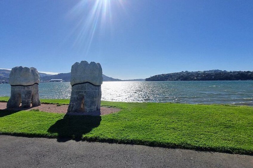 Un área verde con dos grandes estatuas de piedra y un cuerpo de agua al fondo. 2