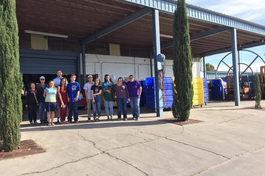 A group of people standing in front of a building with a covered roof and large windows. 3