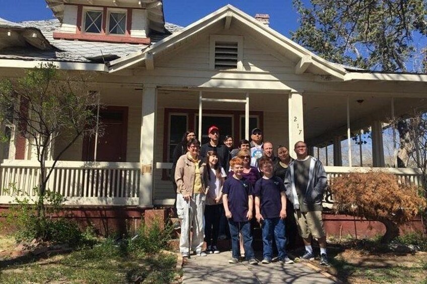 A group of people standing in front of a house with a porch and a number '217' on the wall. 4