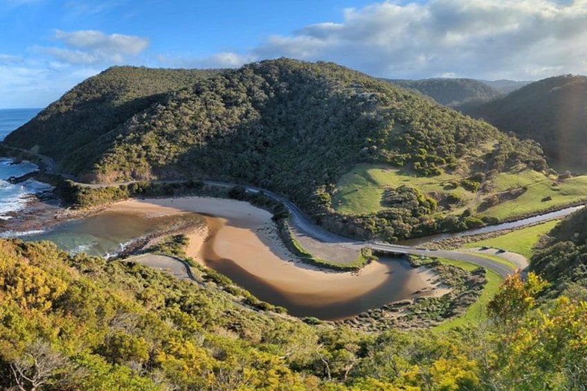 A winding river, a beach, and a forested hill. 1