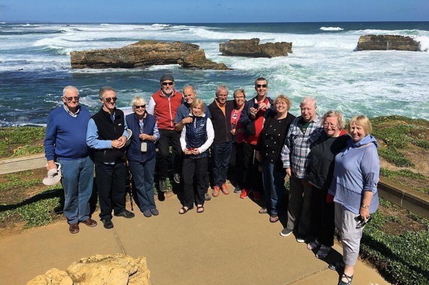 A group of people standing on a coastal path with ocean waves in the background. 2