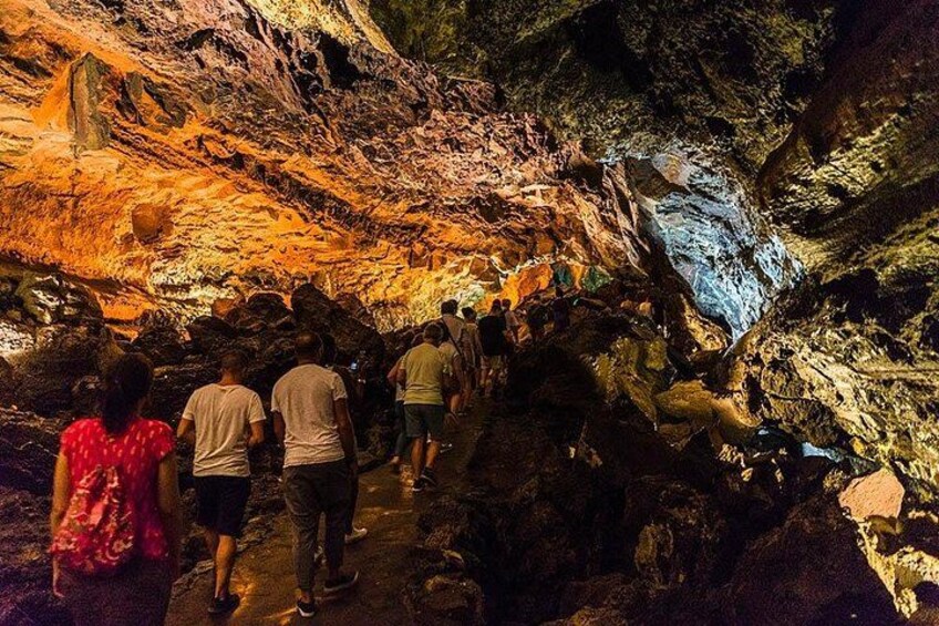 A group of people walking through a cave with colorful rock formations. 5