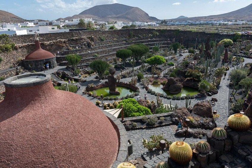 A terraced garden with cacti, a red-roofed structure, and a mountainous backdrop. 3