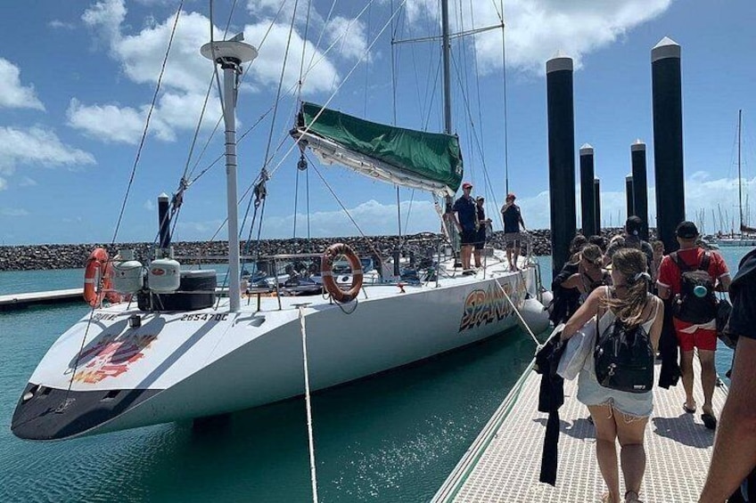 A sailboat docked at a pier with people walking on the dock. 2