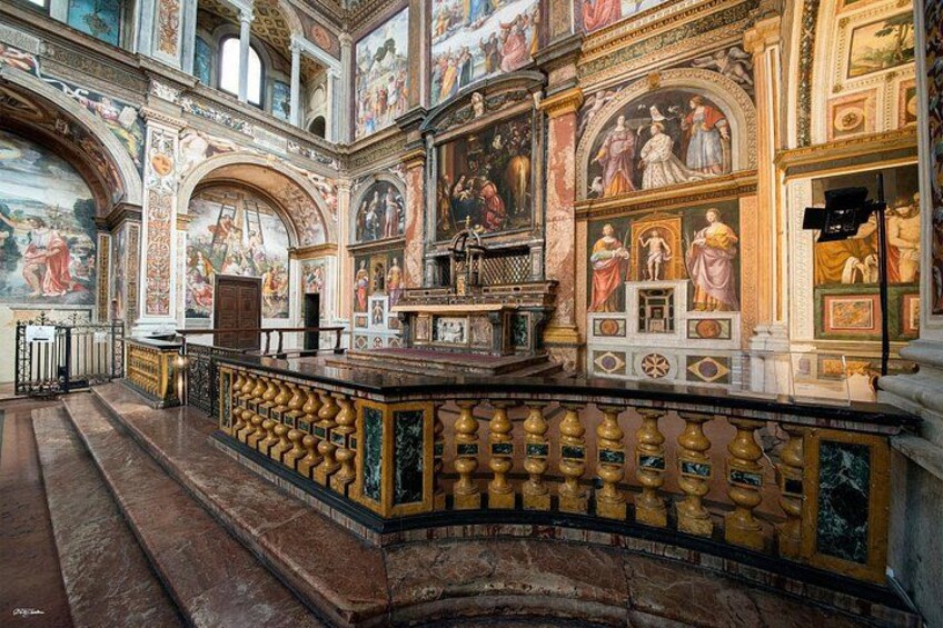 An ornate church interior with detailed frescoes, a wooden pulpit, and a marble floor. 2