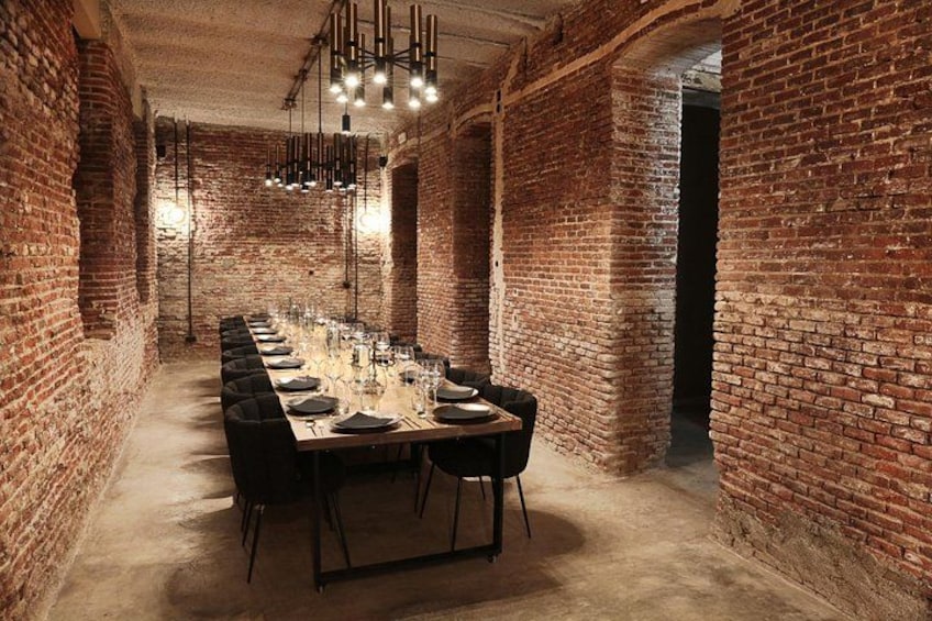 Una larga mesa de comedor en una habitación con paredes de ladrillo y lámparas colgantes. 2