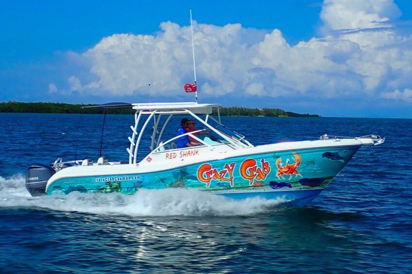 A boat named 'Red Shark' with 'Crazy Cab' written on its side, moving on water with a clear sky and distant land in the background. 3