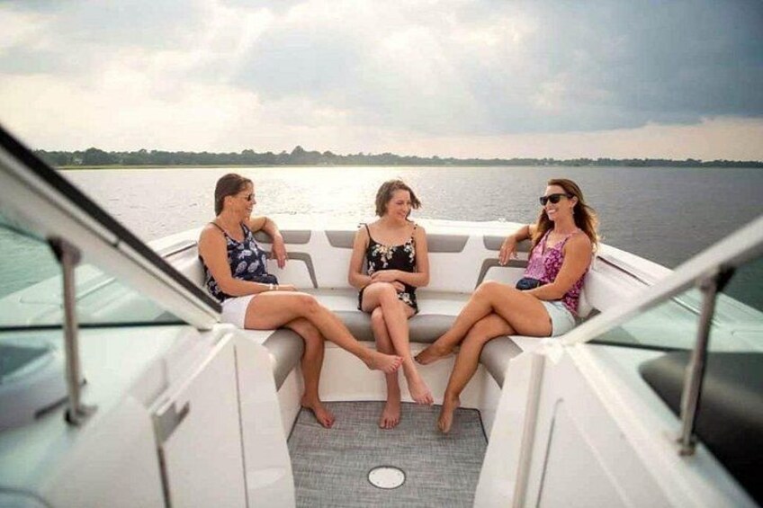 Three people on a boat with a body of water and a distant shoreline in the background. 2