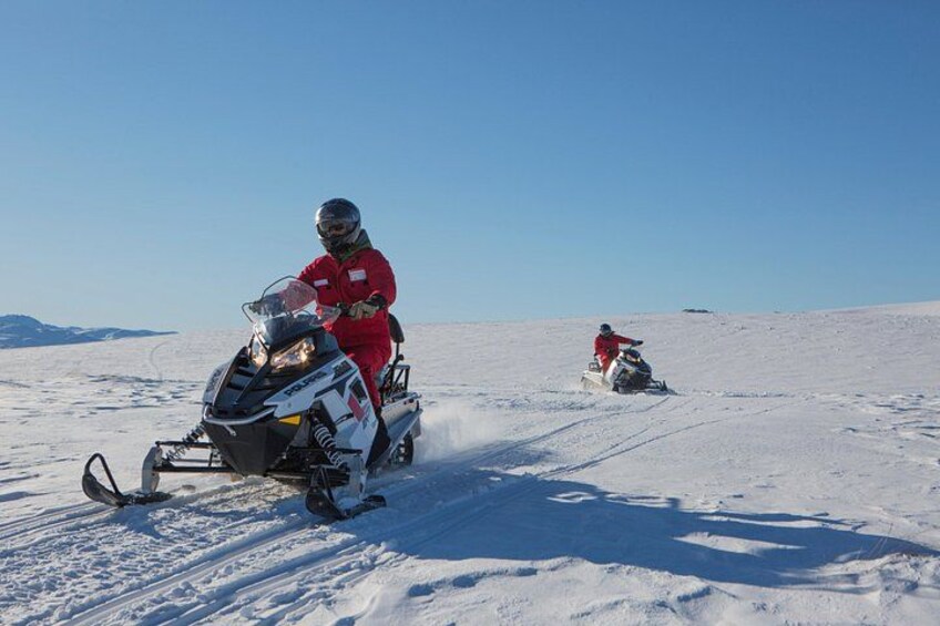 Two snowmobiles on a snowy landscape with a clear sky. 2