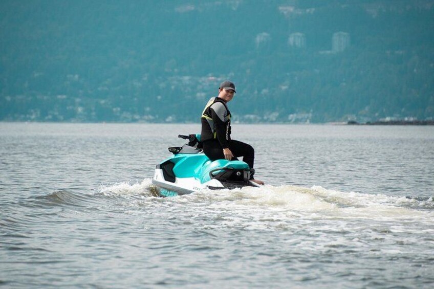 A person riding a jet ski on a body of water with a hilly landscape in the background. 3