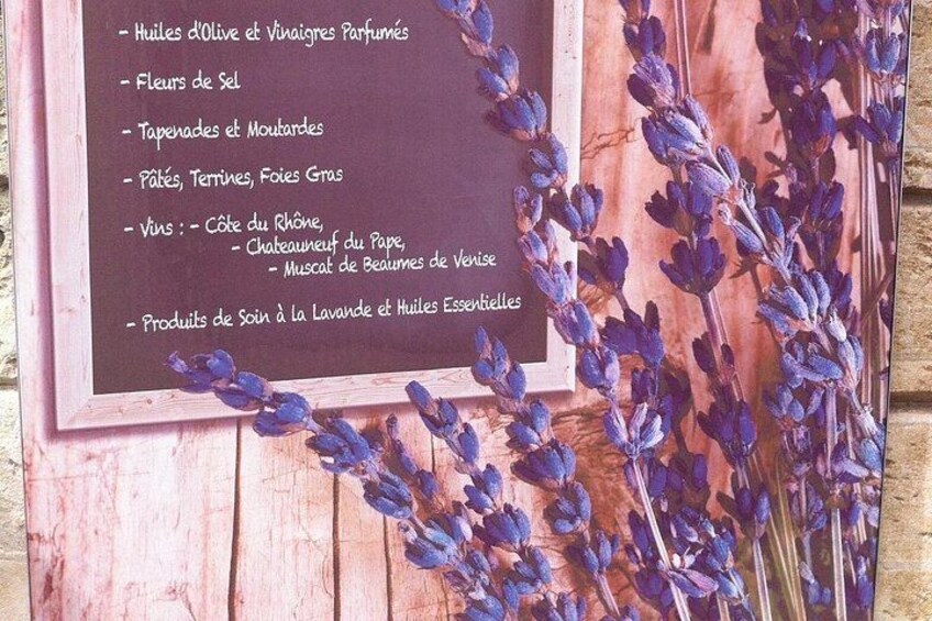 A wooden board with a list of lavender products and a branch of lavender flowers. 3