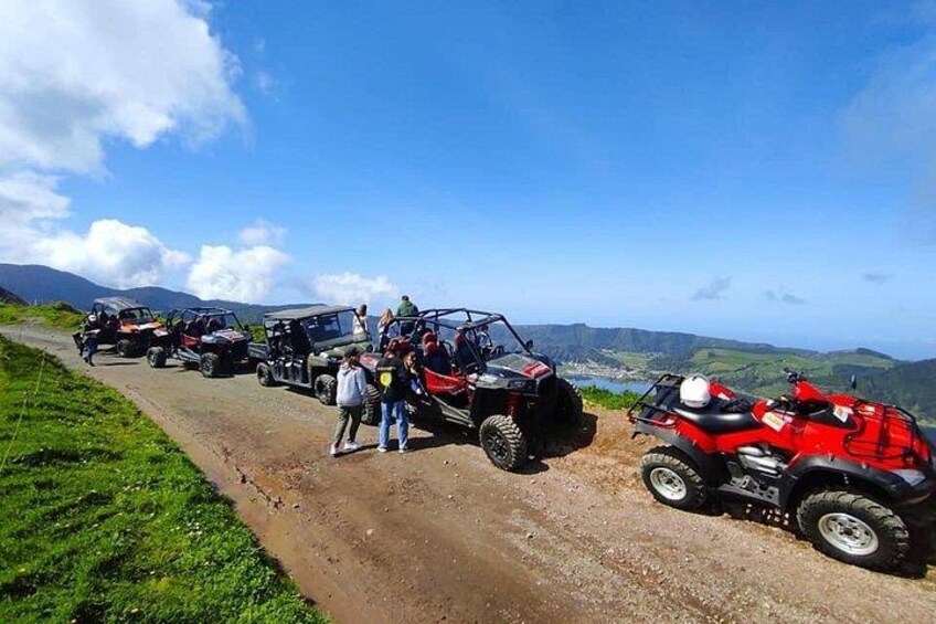 A group of off-road vehicles on a dirt road with a mountainous landscape in the background. 3