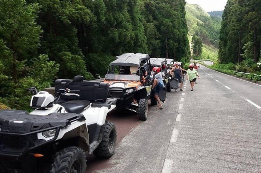 ATVs parked on a road with people walking. 2