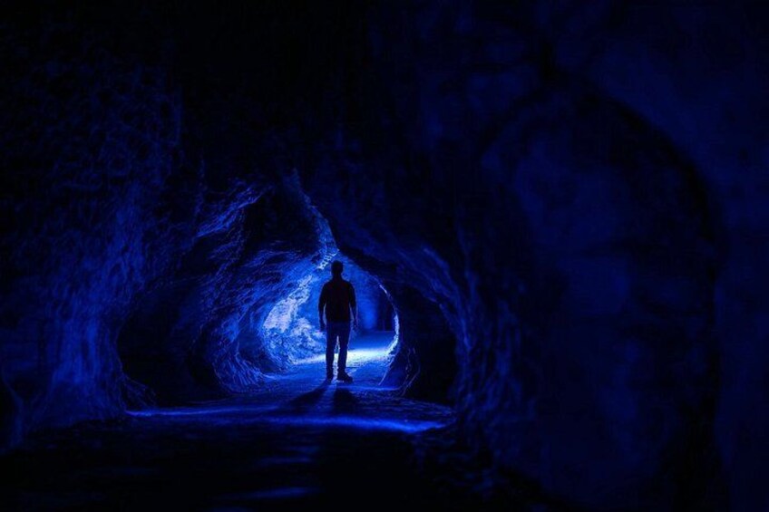 A person standing in a cave illuminated by blue light. 3