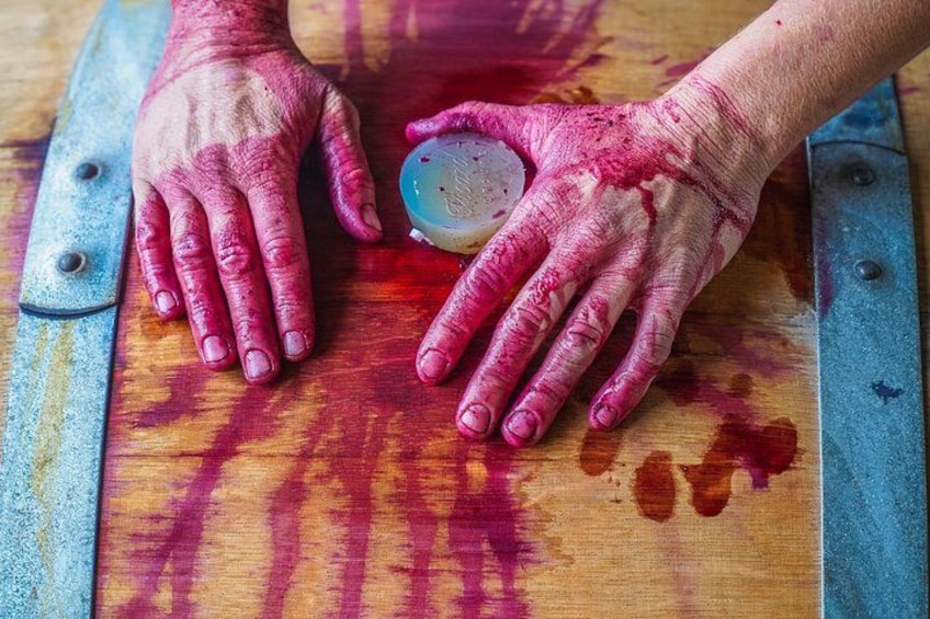 Hands with red paint stains on a wooden surface. 2