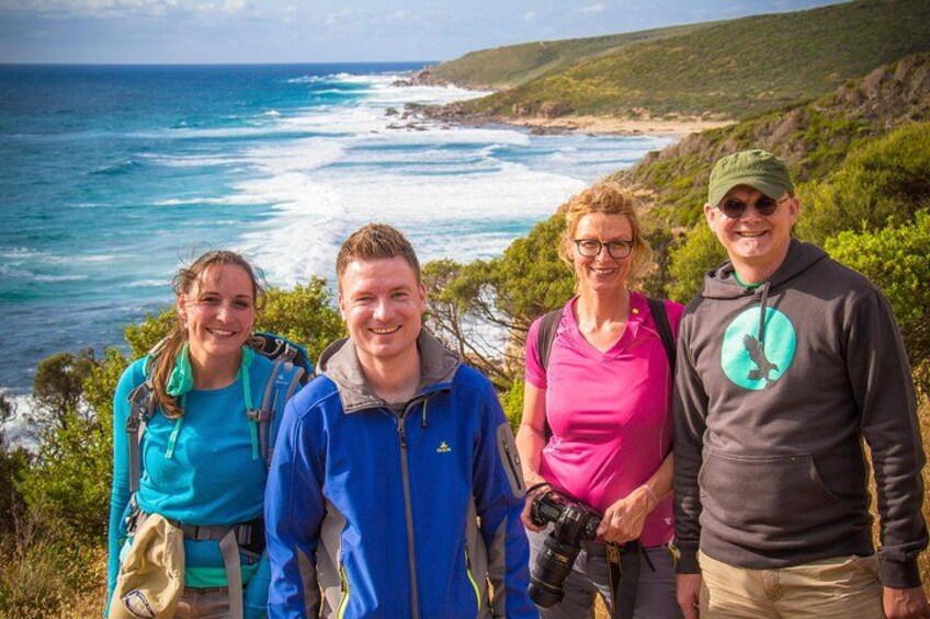 Four people standing on a cliff overlooking the ocean. 5